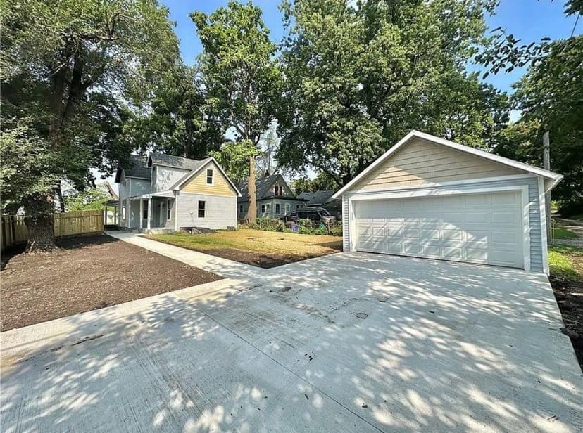 Newly renovated grey house with garage and landscaped yard under clear blue skies.